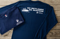 Navy blue t-shirt with white text and graphics on a wooden surface