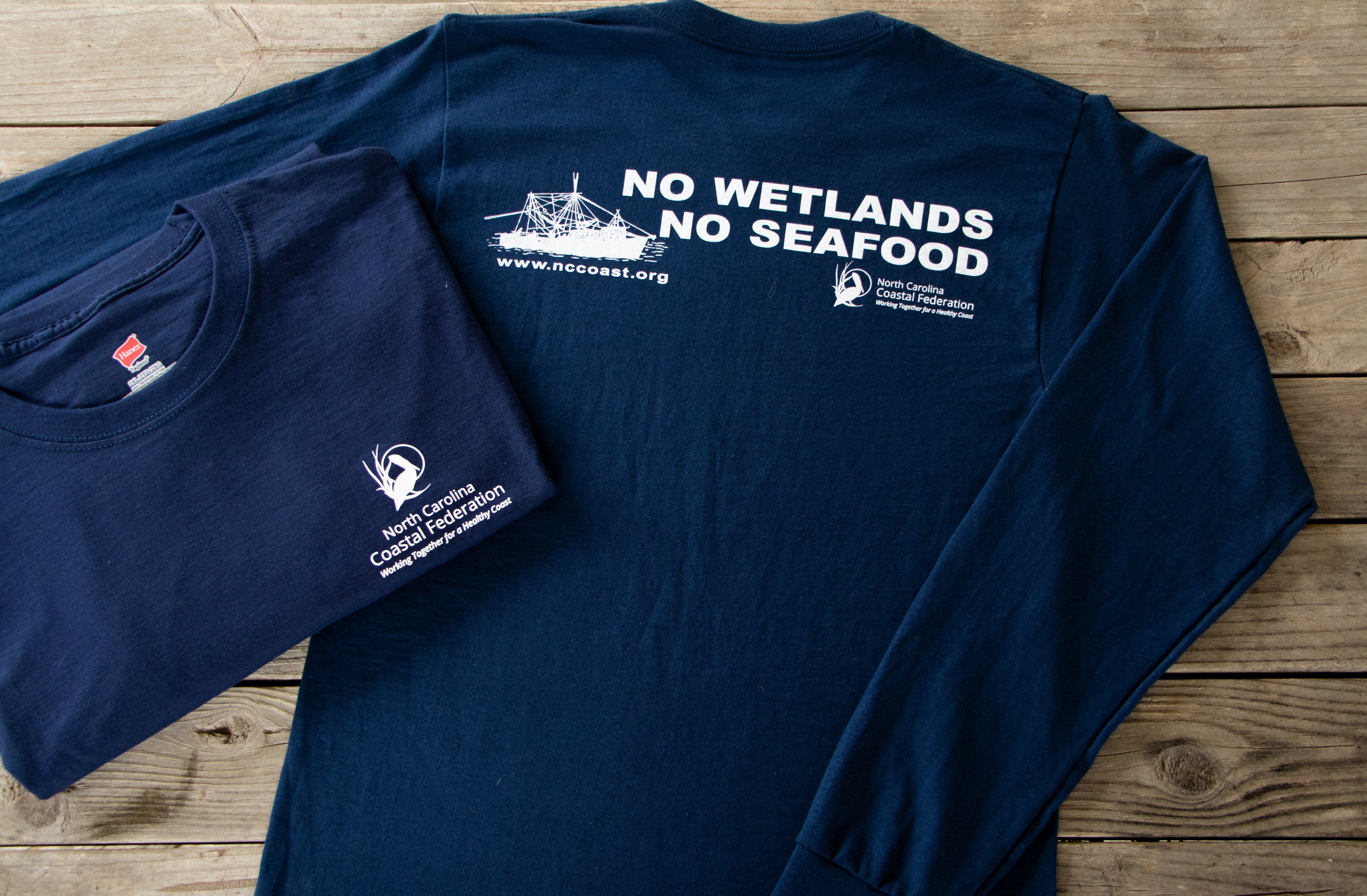 Navy blue t-shirt with white text and graphics on a wooden surface