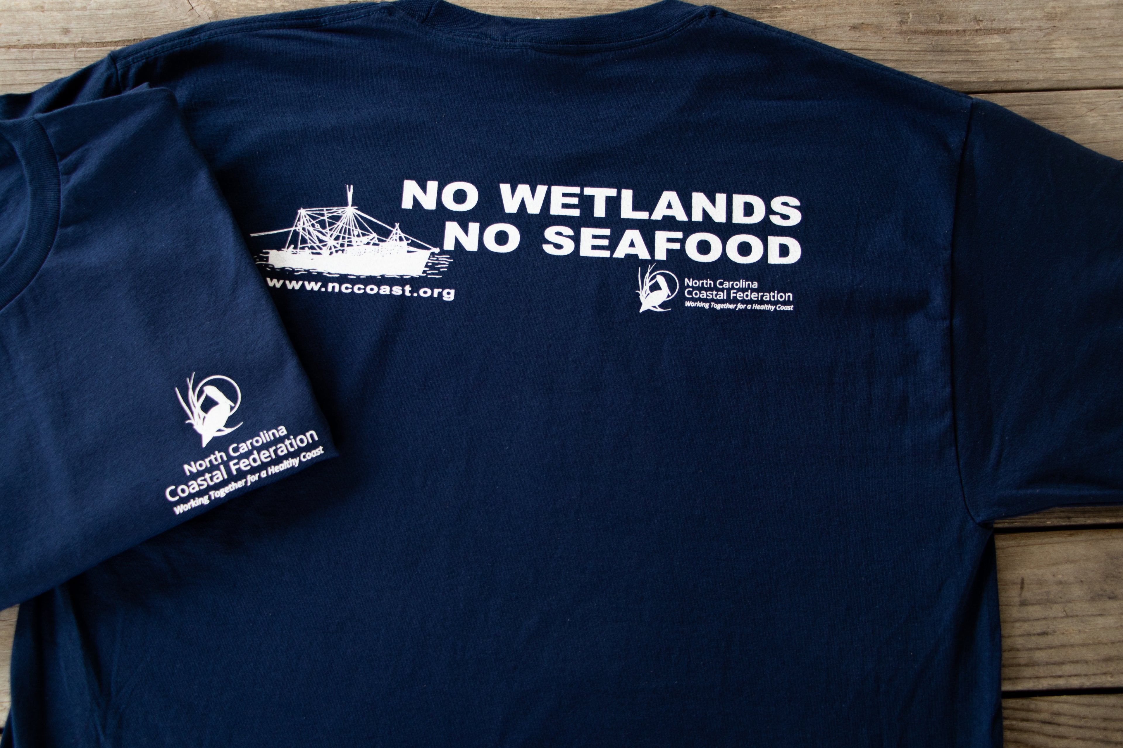 Navy blue t-shirt with white text and graphics on a wooden surface