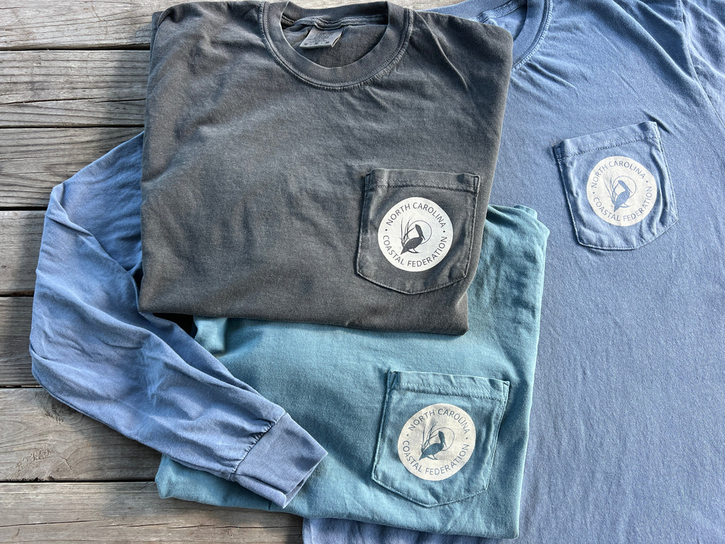 Folded blue and gray t-shirts with a logo on a wooden surface